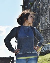 Young woman standing by historic building against sky