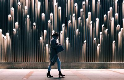 Full length rear view of man walking in illuminated building