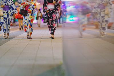 Low section of people walking on multi colored pencils