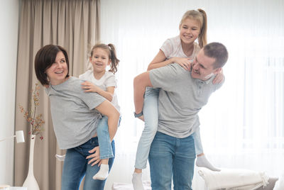 Parents piggybacking daughters at home