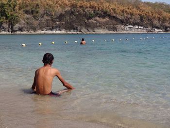 Rear view of shirtless man in sea