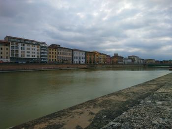 Buildings by river against sky in city