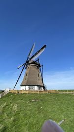 Low angle view of windmill against clear blue sky