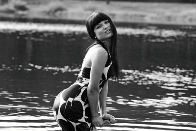 Side view of young woman standing by lake