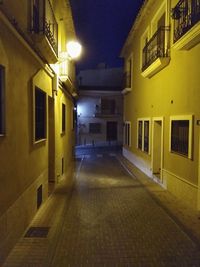 Empty alley along buildings at night