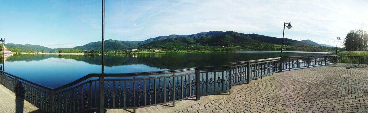 mountain, water, railing, lake, tranquility, sky, tranquil scene, mountain range, scenics, beauty in nature, nature, reflection, river, tree, sunlight, pier, blue, idyllic, day, built structure