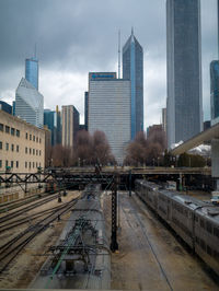 Railroad tracks amidst buildings in city against sky