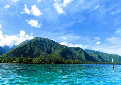 Scenic view of sea and mountains against blue sky