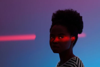 Fashion neon light studio portrait of young african american girl with ethnic high puff hairstyle