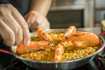 Cropped image of chef arranging shrimp on paella in container