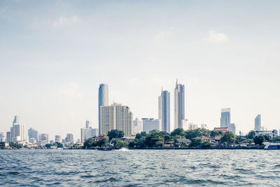 Modern buildings by sea against sky