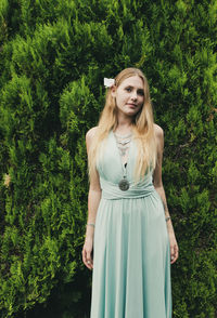 Beautiful young woman standing against trees