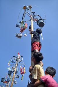 Low angle view of people against clear blue sky