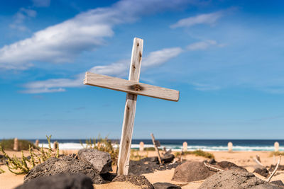 Close-up of cross on beach against sky