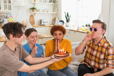 Smiling friends toasting beer while sitting at home