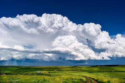 Cumulonimbus thunderstorm clouds build above the rolling, green hills near lusk, wyoming, usa.