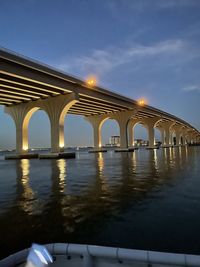 Arch bridge over river against sky during sunset