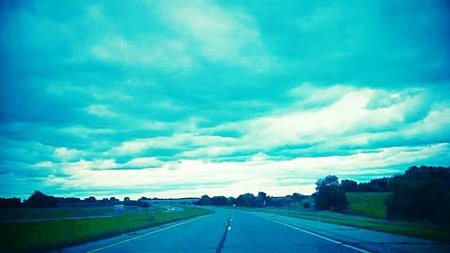 Country road against cloudy sky