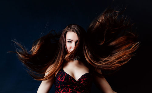 Portrait of young woman against black background