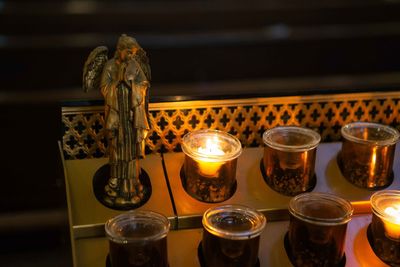 Close-up of angel figurine with tea light candles in darkroom