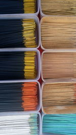 Full frame shot of various incense sticks in plastic containers for sale