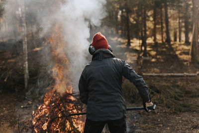 Rear view of person burning branches in forest