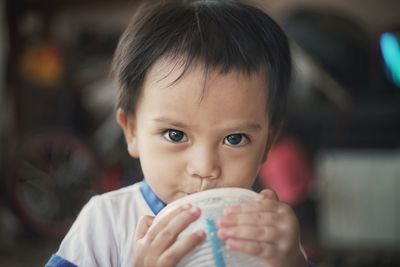 Portrait of cute boy drinking from disposable cup at home