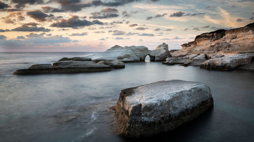 Rocky seashore seascape with wavy ocean and dramatic sunset at  coastal area in paphos, cyprus