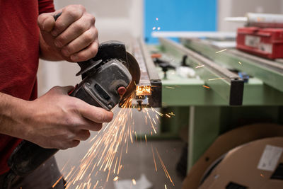 Midsection of man cutting metal in workshop