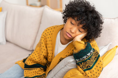 Side view of woman sitting on bed at home