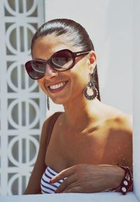 Portrait of smiling young woman in sunglasses standing outdoors