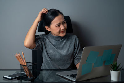 Young woman using mobile phone while sitting on table