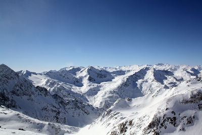 Scenic view of snowcapped mountains against clear blue sky