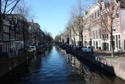 Canal amidst buildings in city against sky