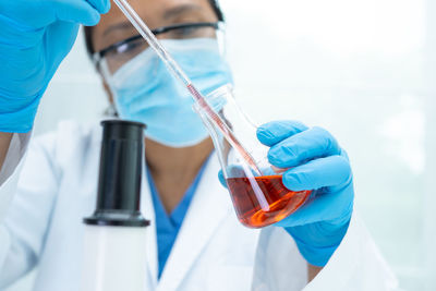 Midsection of scientist examining chemical in laboratory