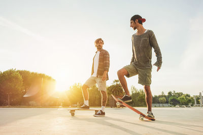 Young friends skateboarding on park