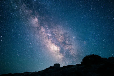 Low angle view of silhouette mountain against star field at night