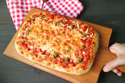 Hand placing fresh baked pizza alla pala roman-style pizza on a paddle on the table