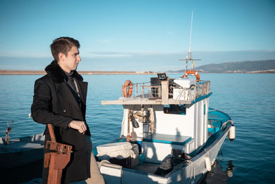 Side view of man standing by nautical vessel against sky