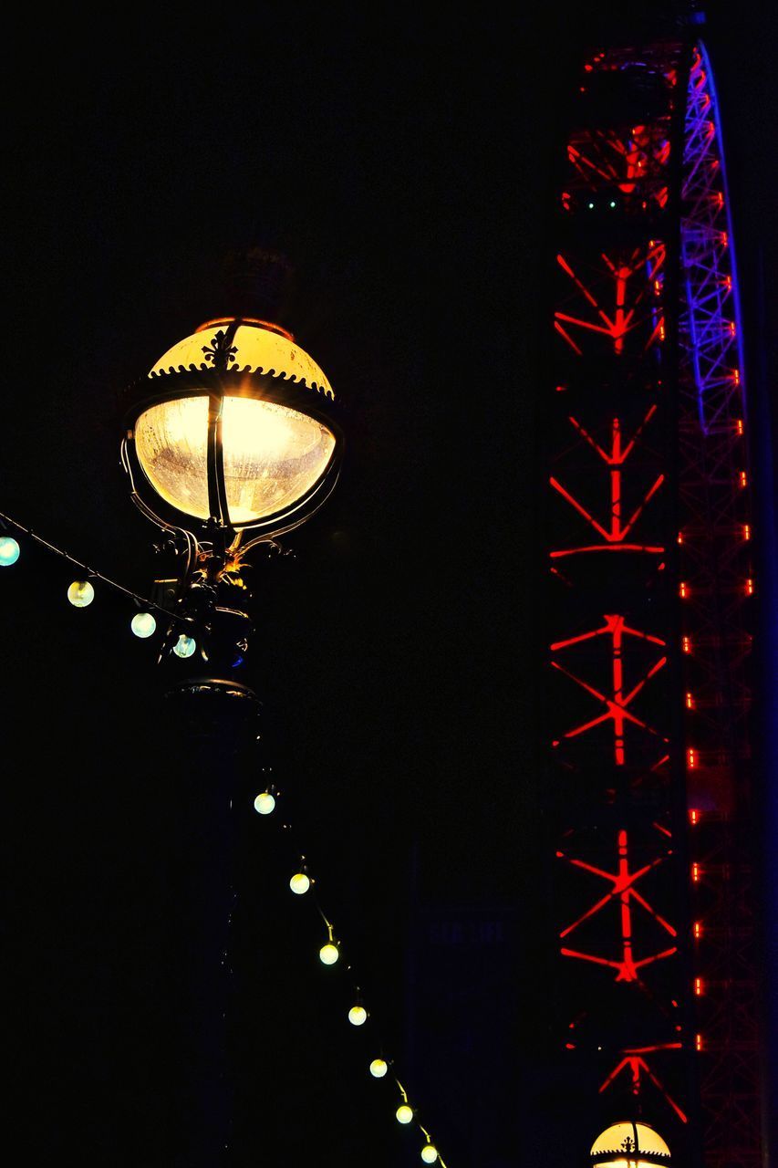 LOW ANGLE VIEW OF ILLUMINATED TOWER AGAINST DARK SKY