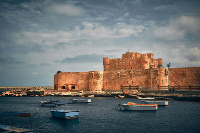 Boats in a harbor in front of qaitbay fort. citadel of qaitbay, alexandria, egypt