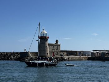 Boats in sea against clear blue sky