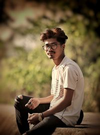 Young man using mobile phone sitting outdoors