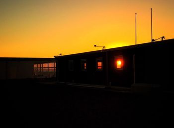 Silhouette built structure against orange sky