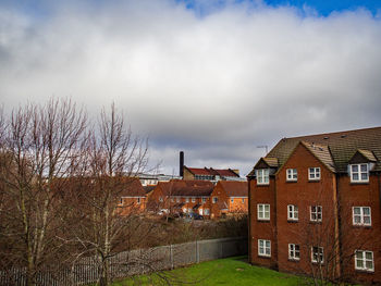 Houses amidst trees and buildings against sky