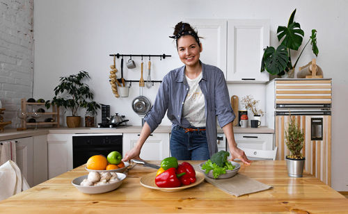 Young and beautiful housewife woman cooking in a white kitchen