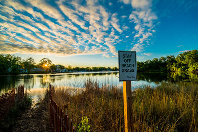 Information sign by lake against sky