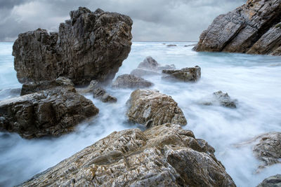 Scenic view of rocks in sea against sky