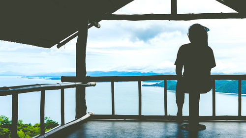 Rear view of woman looking at swimming pool against sky