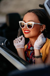 Portrait of young woman wearing sunglasses while sitting in car